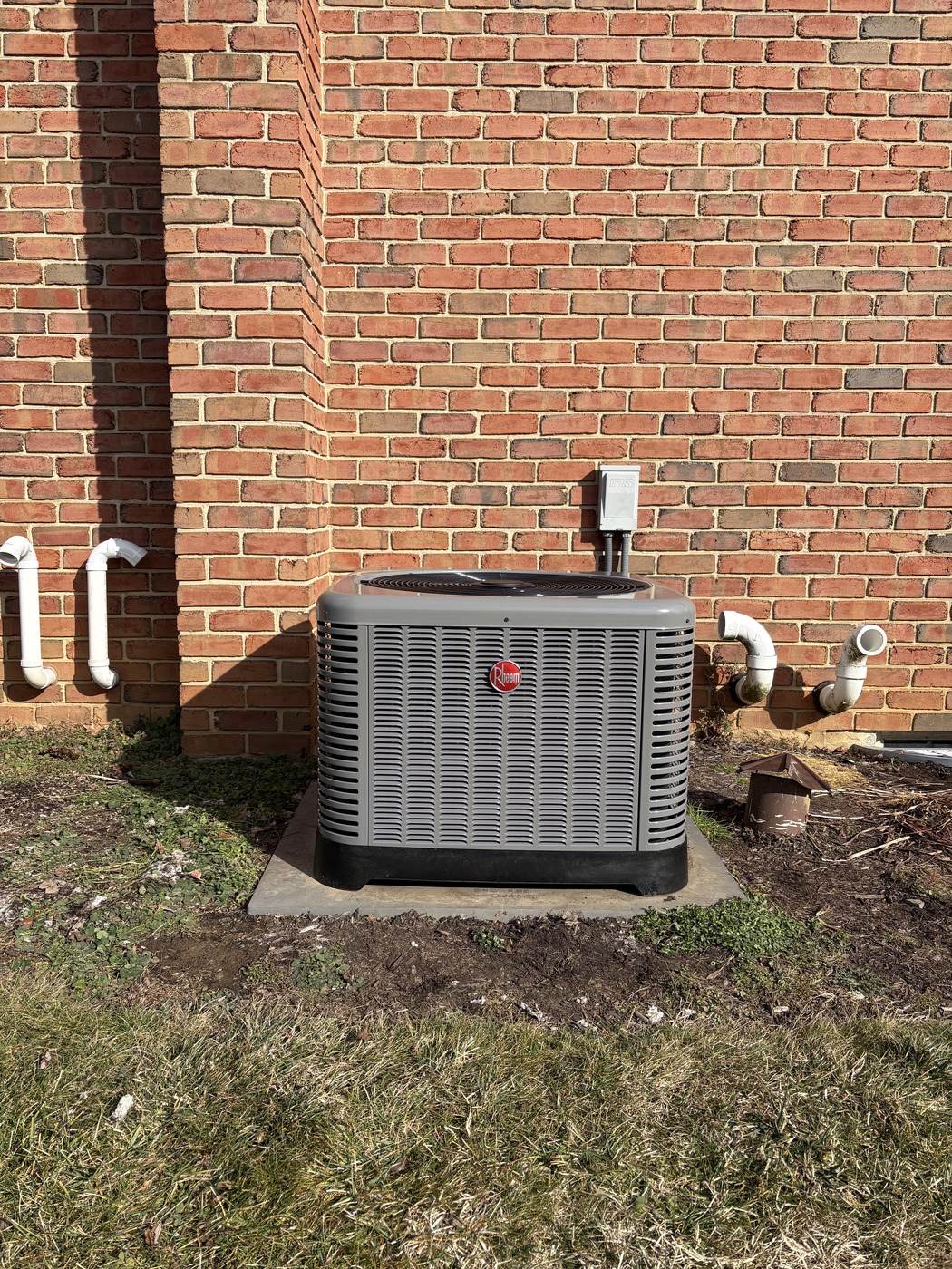 New Rheem air-conditioning condenser on a pad, installed by Tom Falk.