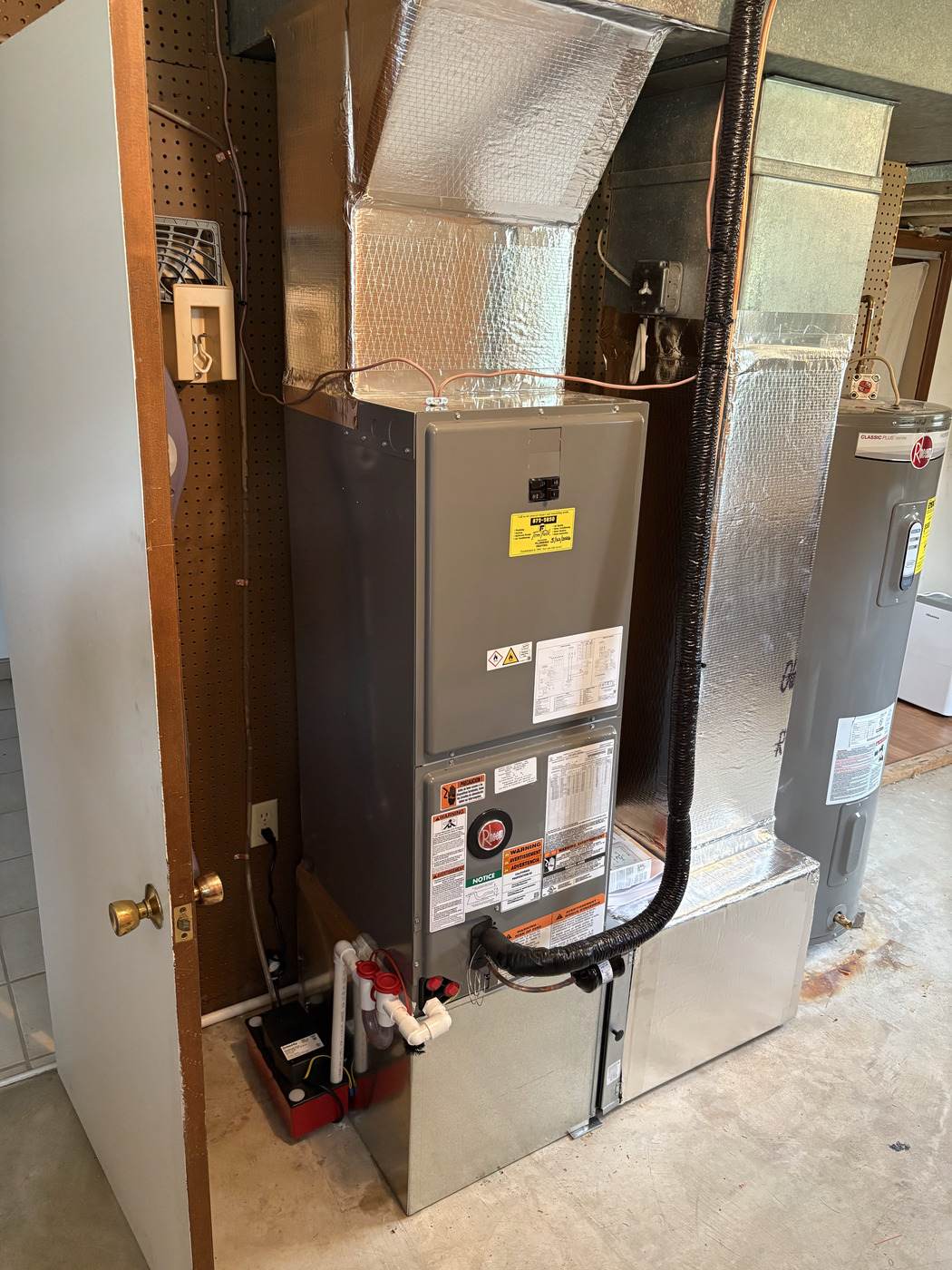 Rheem electric water heater beside a Rheem air handler, installed by Tom Falk.