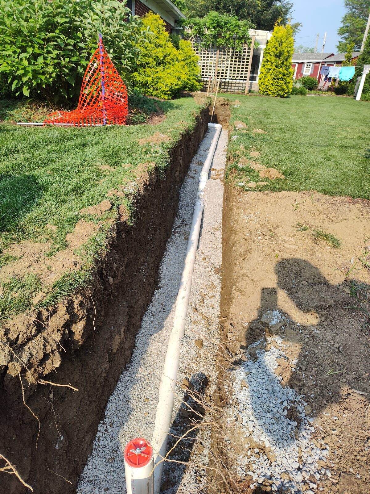 A new water service line bedded in gravel in an open trench running across a Lancaster County yard.