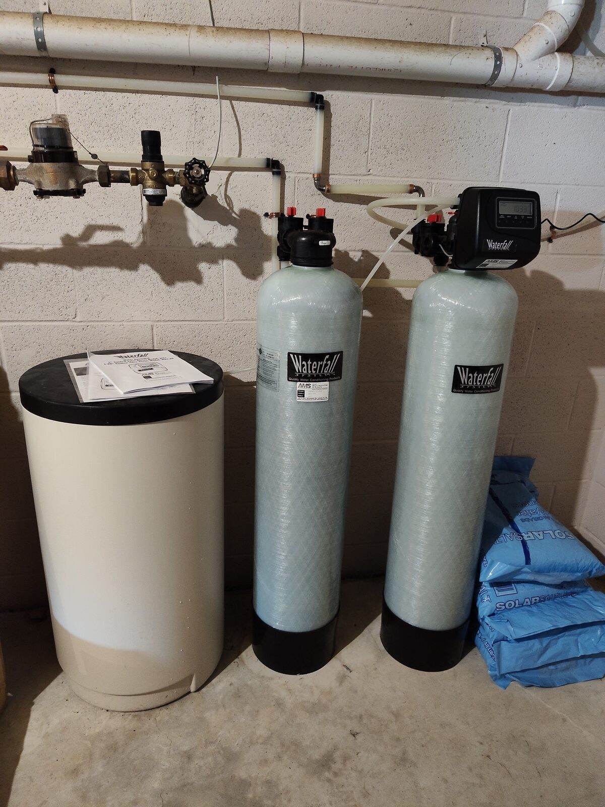 A newly installed water treatment system with twin fiberglass softener tanks and a brine tank in a Lancaster County basement.
