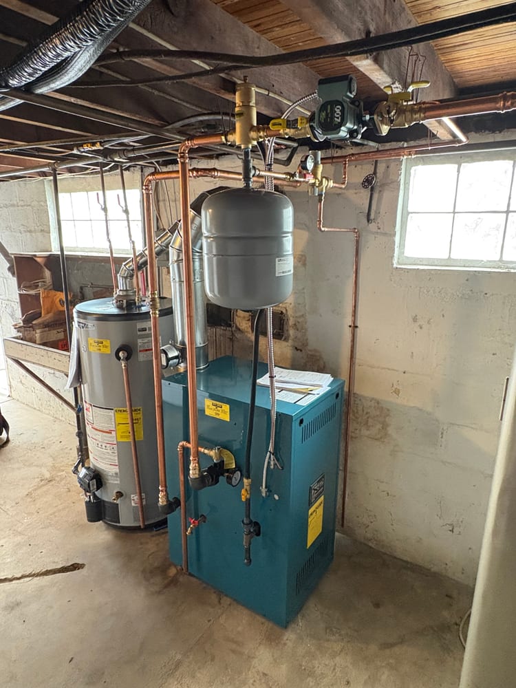 A newly installed hot-water boiler and gas water heater with fresh copper piping in a Millersville basement.