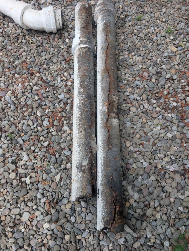 A length of cast iron drain pipe removed from a Lancaster building, split down its side from decades of internal corrosion.