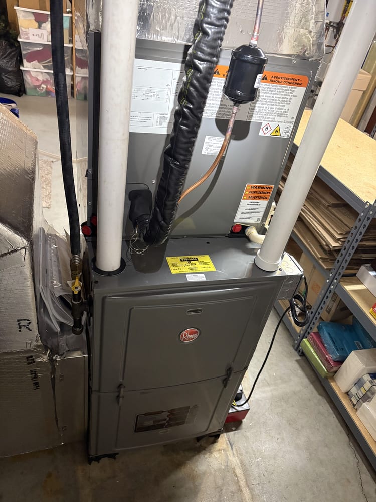 A Rheem gas furnace installed by Tom Falk, with the company's yellow service tag on the cabinet.
